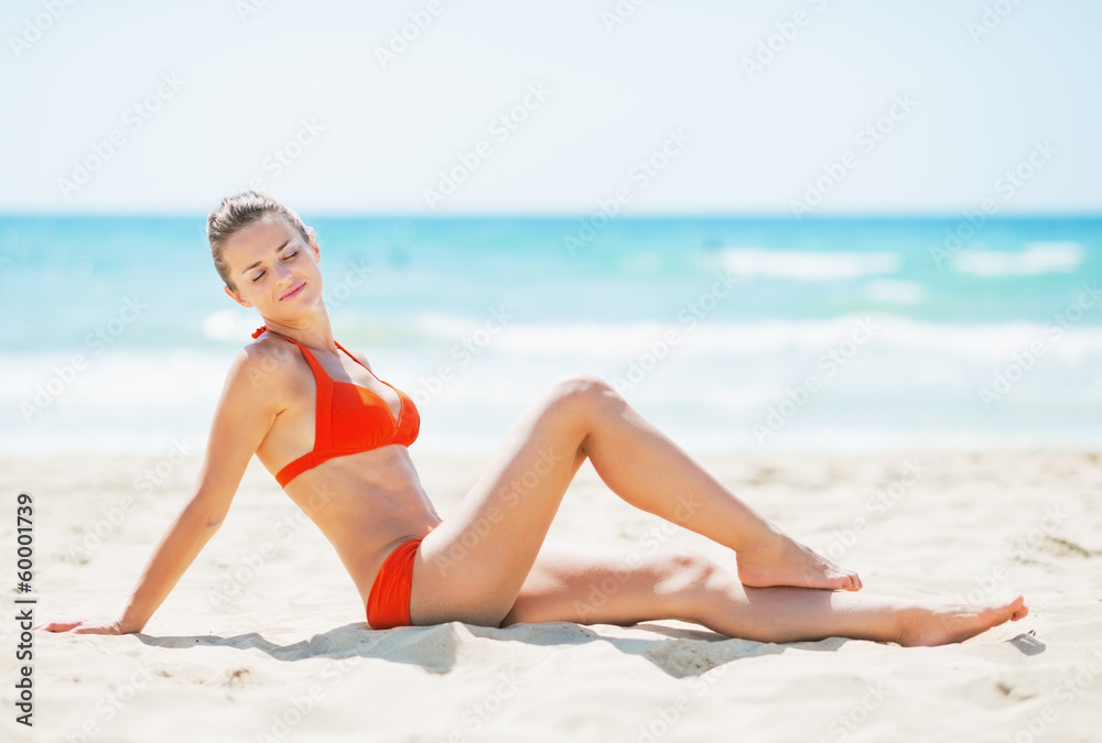 Happy young woman sitting on beach
