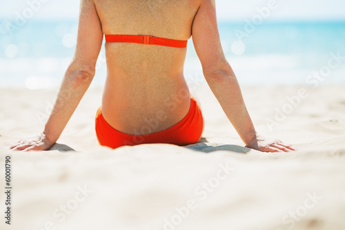 Closeup on young woman sitting on beach. rear view