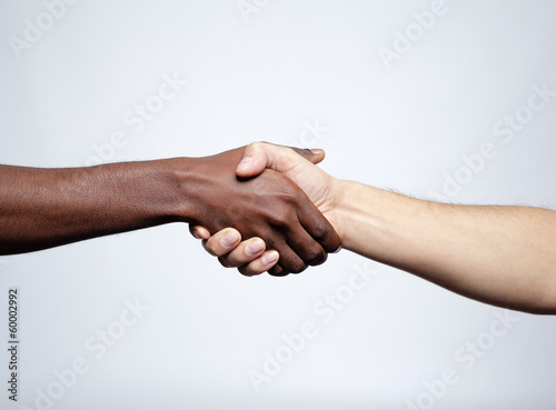 Handshake between african and a caucasian man over gray backgrou