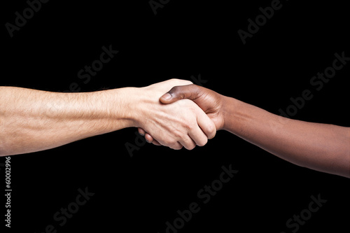 Handshake between african and a caucasian man against dark backg