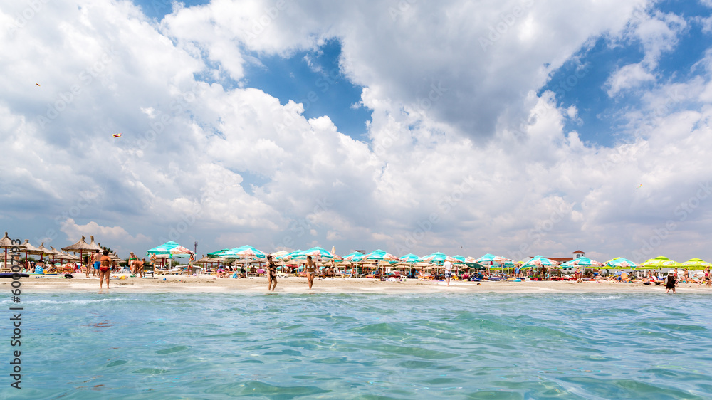 White clouds and blue sky above a crowded sandy beach