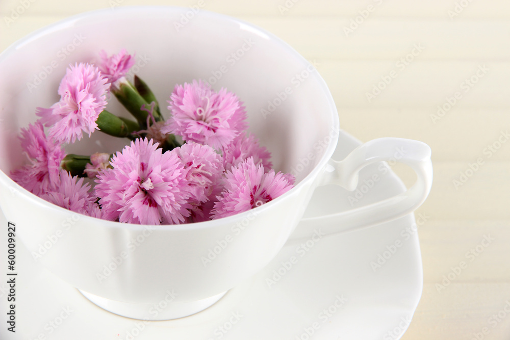 Many small pink cloves in cup on wooden background Many small pink cloves in cup on wooden background
