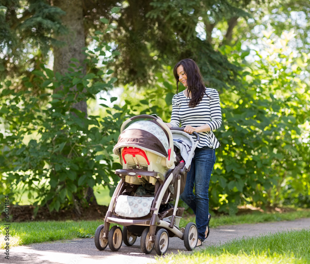 Woman Pushing Baby Carriage In Park Woman Pushing Baby Carriage In Park