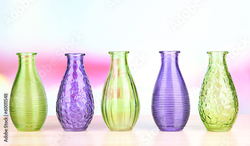 Different decorative vases on shelf on light background