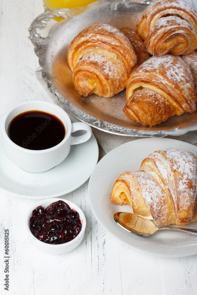 Croissants with jam and coffee on wooden table still life