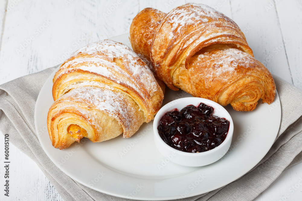 Fresh croissants with jam and sugar powder