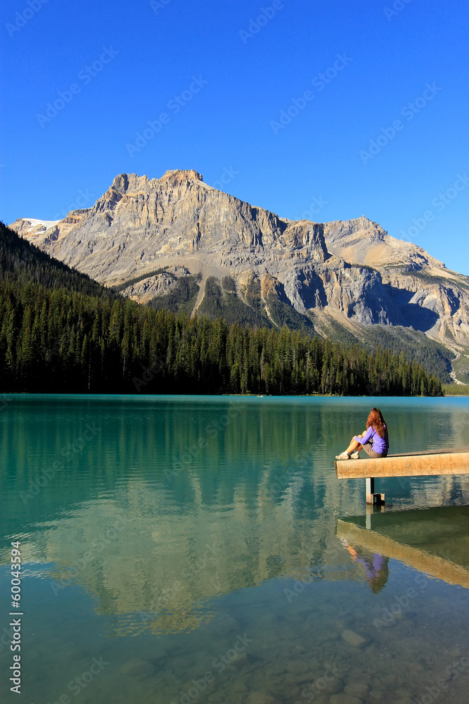 Young woman sitting on a pier at Emerald Lake, Yoho National Par
