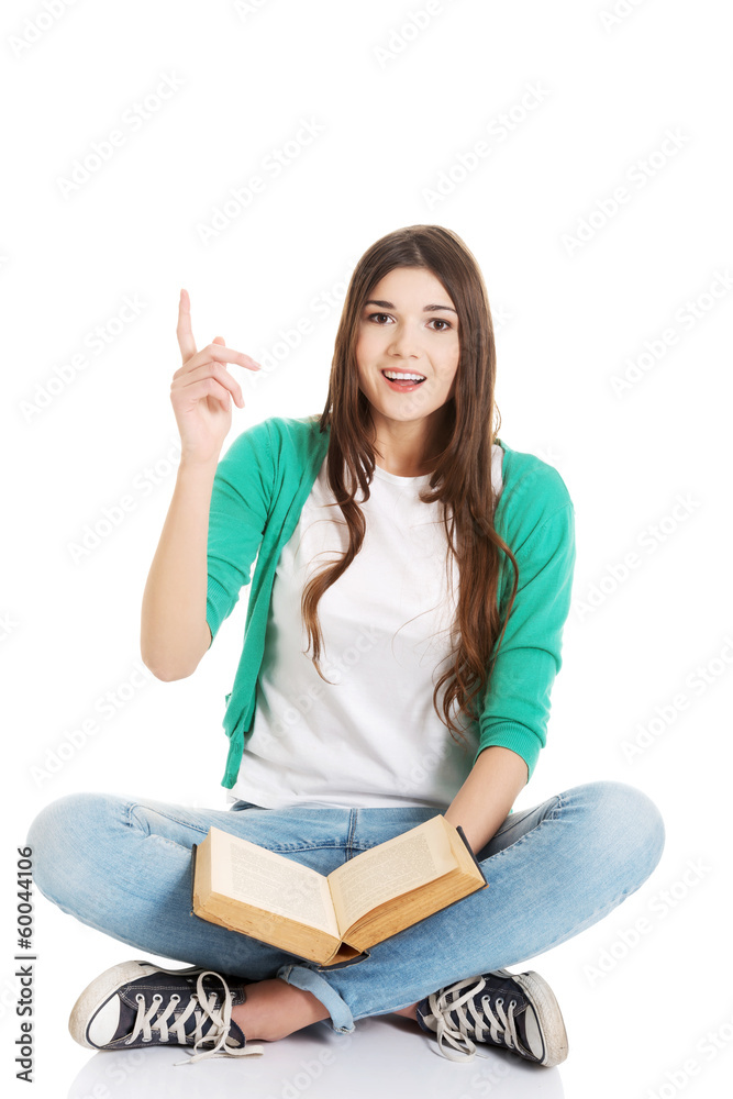 Young beautiful woman student sitting with book and pointing up. Young beautiful woman student sitting with book and pointing up.