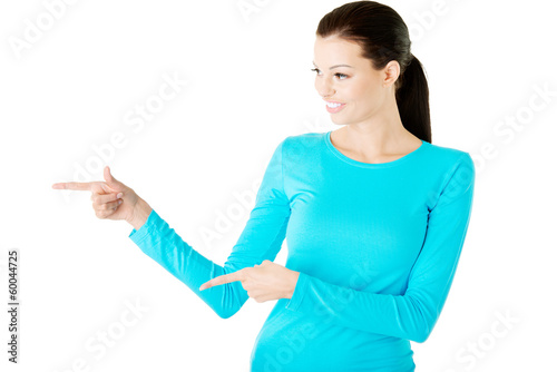 Young casual woman pointing aside.