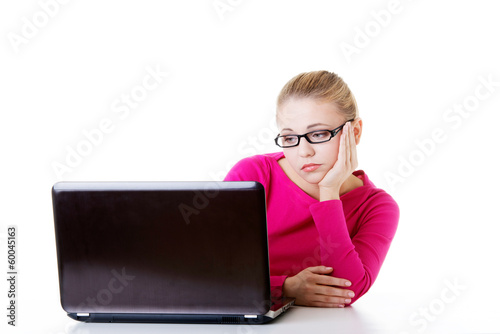 Bored, sad woman sitting in front of laptop.