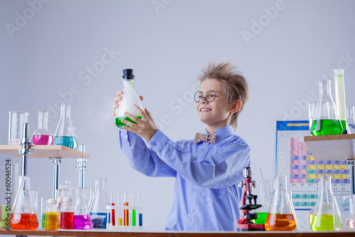 Obraz na płótnie Funny smiling boy holding flask with reagent