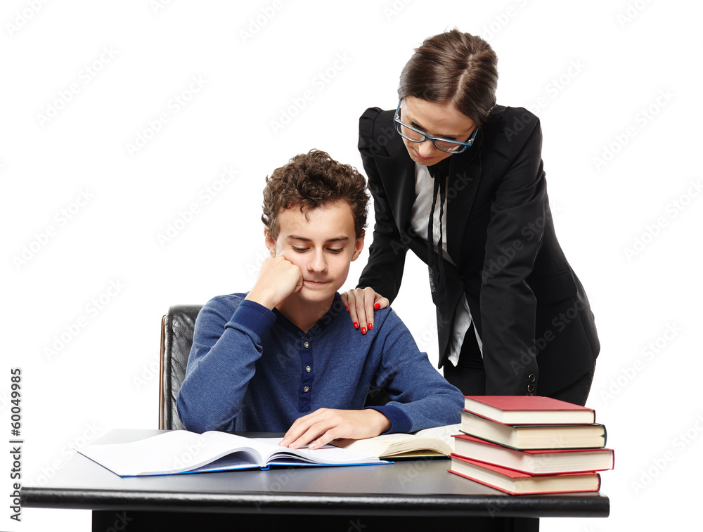 Teacher standing next to student's desk with hand on his shoulde Teacher standing next to student's desk with hand on his shoulde