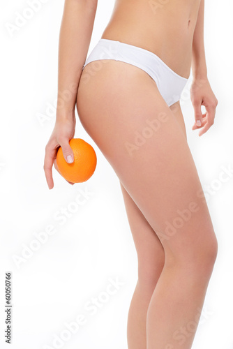 Young woman in underwear with orange showing absence of cellulit