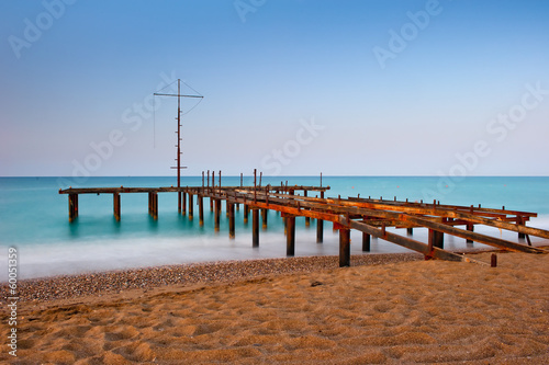 rusty skeleton of the old pier and turquoise sea