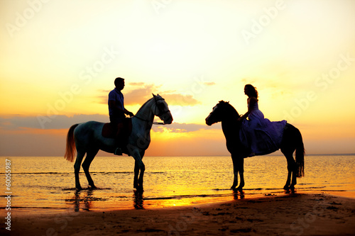 Obraz na plátně Two riders on horseback at sunset on the beach. Lovers ride hors