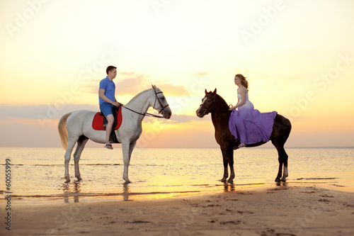 Two riders on horseback at sunset on the beach. Lovers ride hors