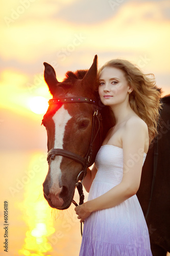 Beautiful woman riding a horse at sunset on the beach. Young gir