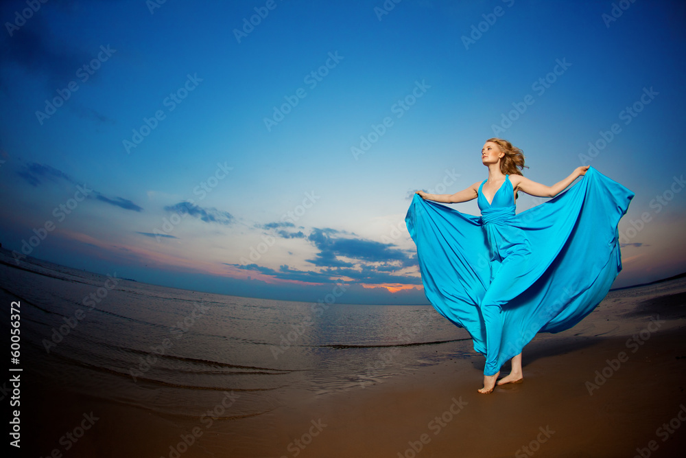 Luxury woman in a long blue evening dress on the beach. Beauty Luxury woman in a long blue evening dress on the beach. Beauty