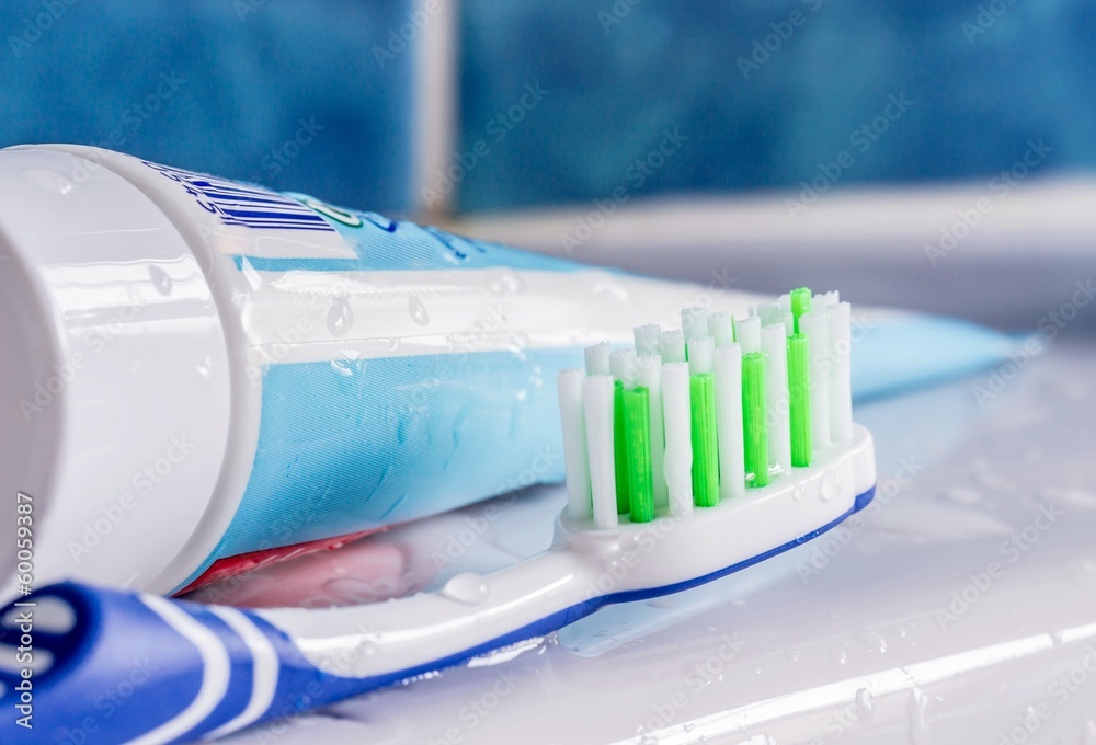 A toothbrush next to a tube of toothpaste at the sink Stock Photo