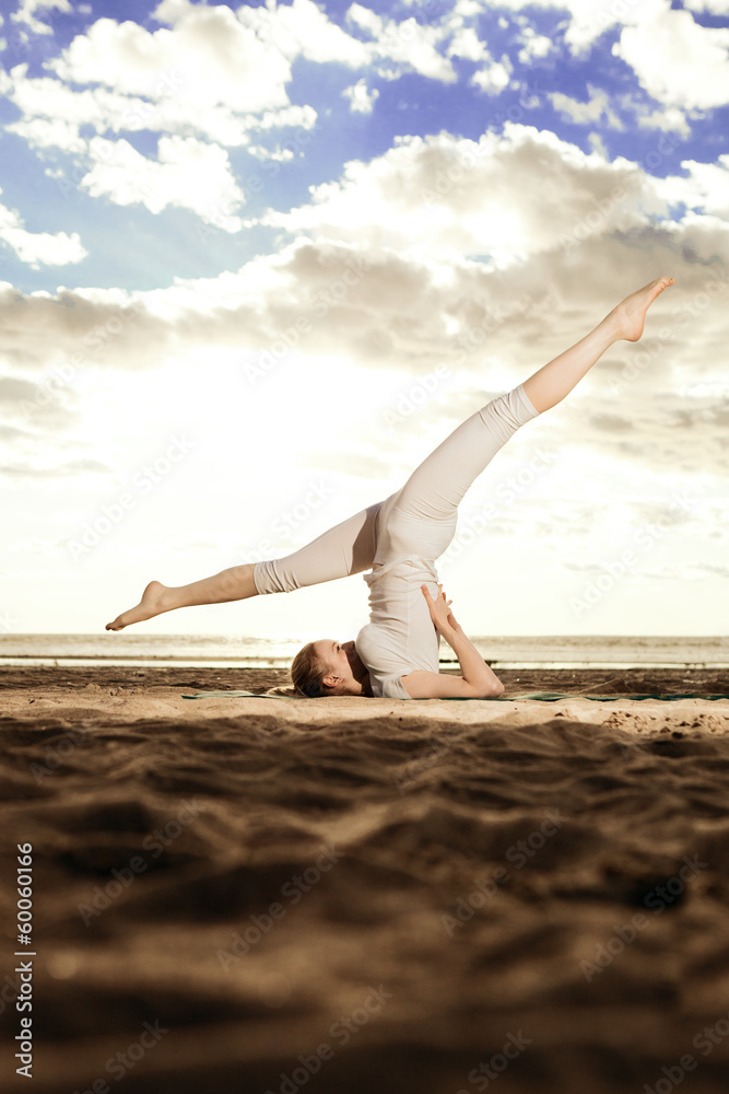 Young beautiful slim woman practices yoga on the beach at sunris Young beautiful slim woman practices yoga on the beach at sunris
