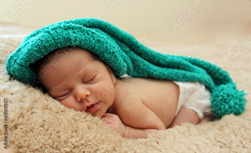 newborn baby is wearing a blue hat and laying down sleeping © dubova
