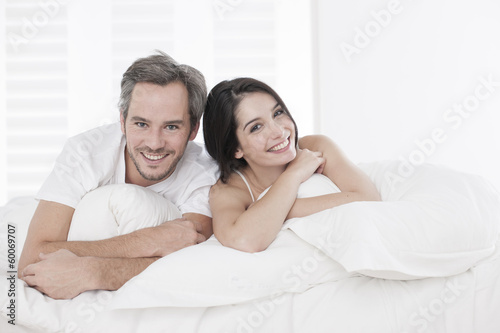 Young couple lying together in bed in the bedroom © jackfrog