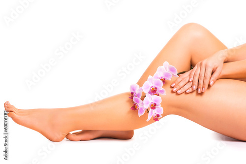 female legs with orchid flower on white