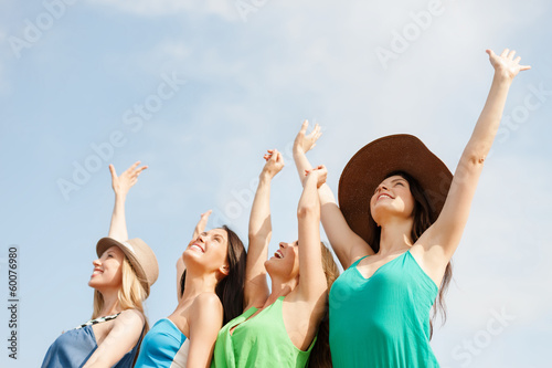 smiling girls with hands up on the beach