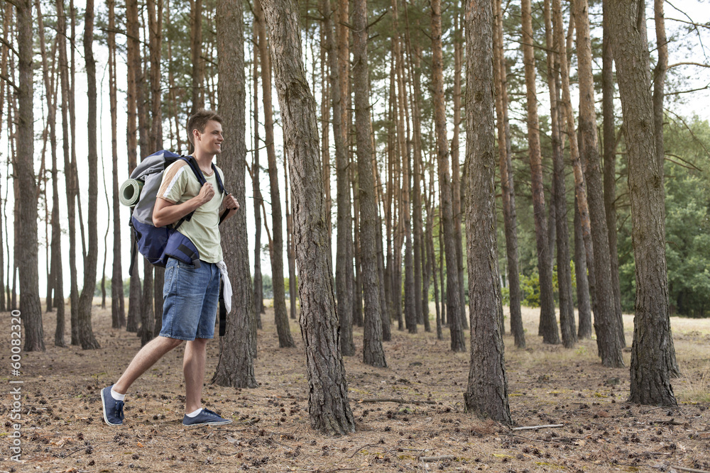 Full length of young man with backpack walking in forest Full length of young man with backpack walking in forest