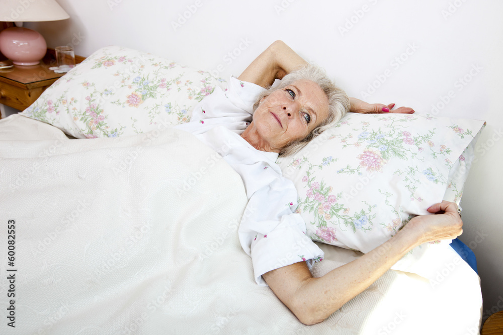 High angle view of senior woman looking away while lying in bed at home High angle view of senior woman looking away while lying in bed at home