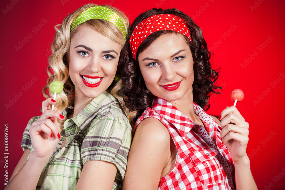 Beautiful pinup girls with lollipop on red background