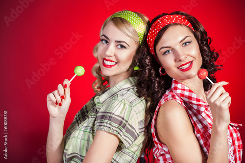 Beautiful pinup girls with lollipop on red background