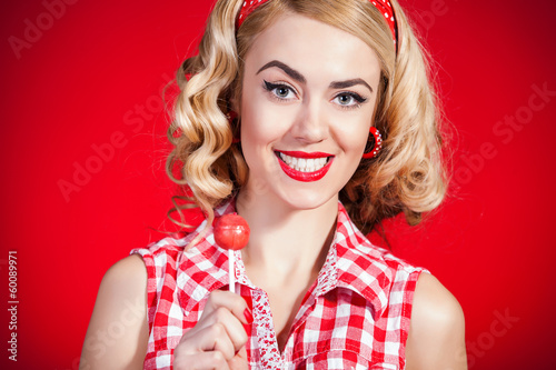 Young pin-up girl with lollipop on red background