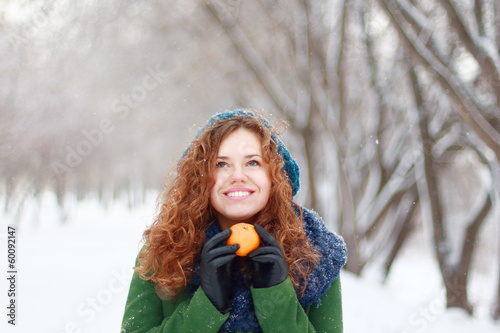Beautiful girl in blue beret holds mandarin and looks up