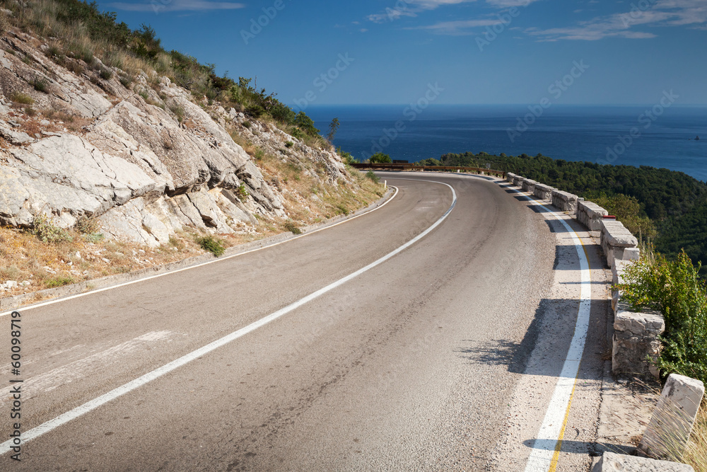 Left turn of mountain highway with blue sky and sea