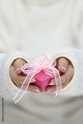 Hands with white long sleeves holding gift wrapped box