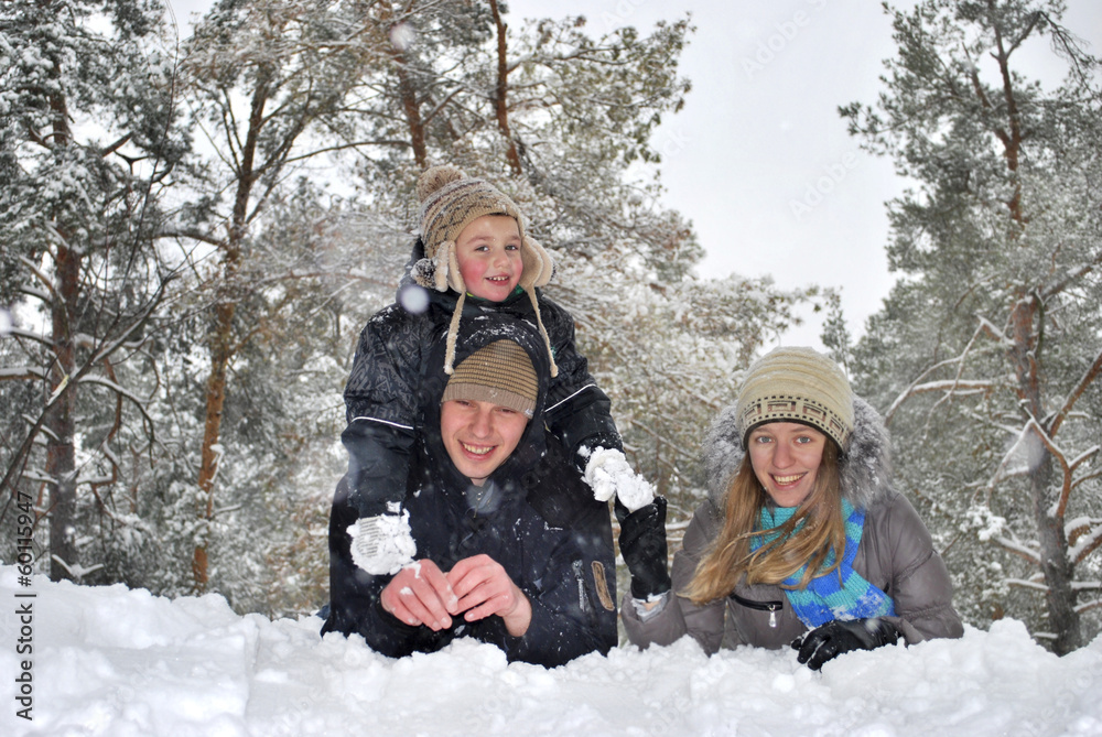 Winter fun. Dad mom and son lie on the snow in the woods near th