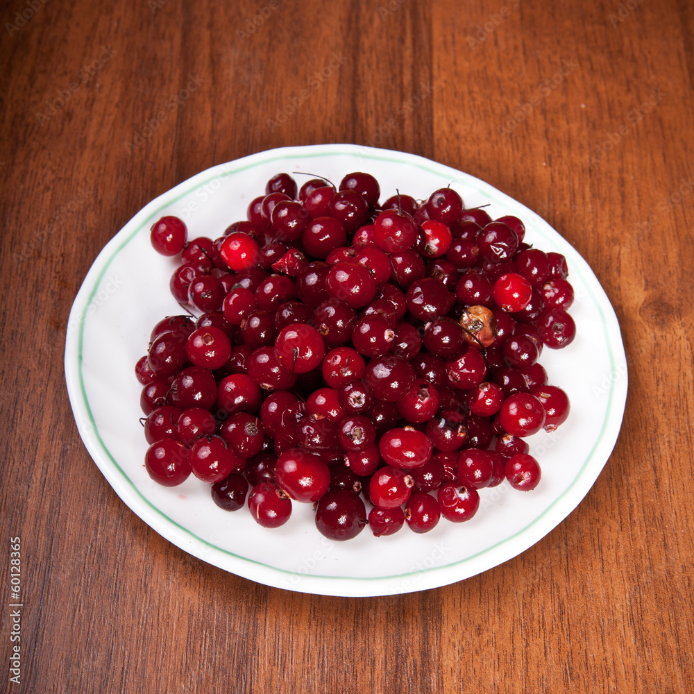 cranberries on a saucer on a wooden background cranberries on a saucer on a wooden background