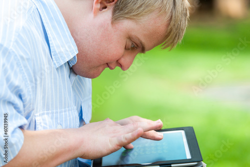 Kid with down syndrome playing on tablet. photo