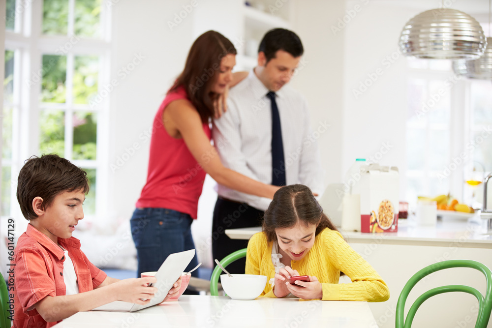 Family Using Digital Devices At Breakfast Table Family Using Digital Devices At Breakfast Table