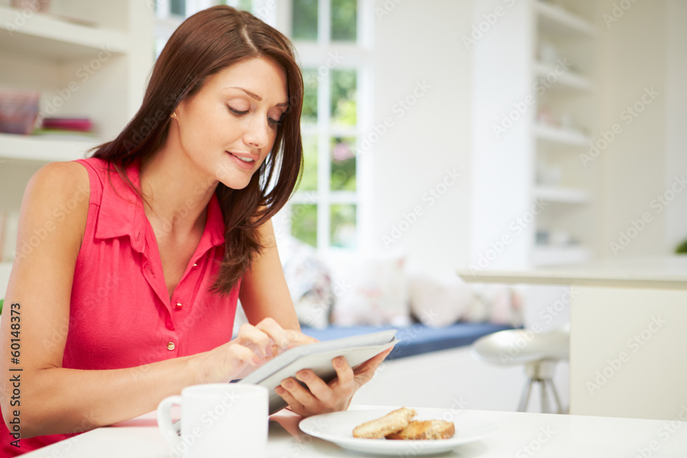Hispanic Woman Using Digital Tablet In Kitchen At Home Hispanic Woman Using Digital Tablet In Kitchen At Home