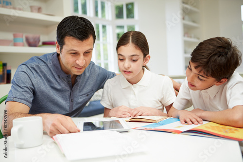 Father Helping Children With Homework Using Digital Tablet