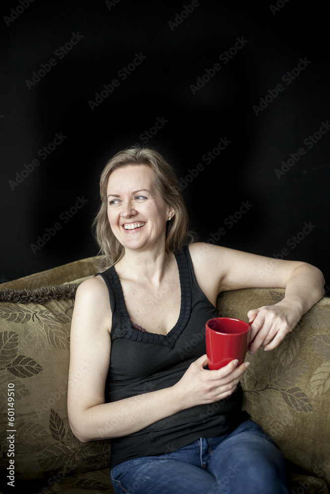 Laughing Blonde Woman with Red Coffee Cup on Black Background