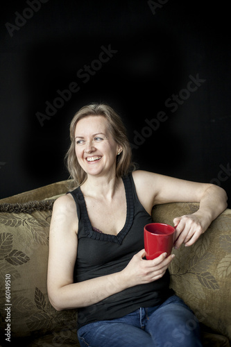 Obraz na płótnie Laughing Blonde Woman with Red Coffee Cup on Black Background w salonie