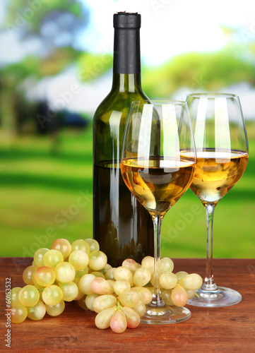 Ripe grapes  bottle and glasses of wine  on bright background