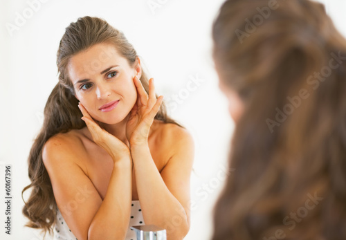Young woman checking facial skin condition