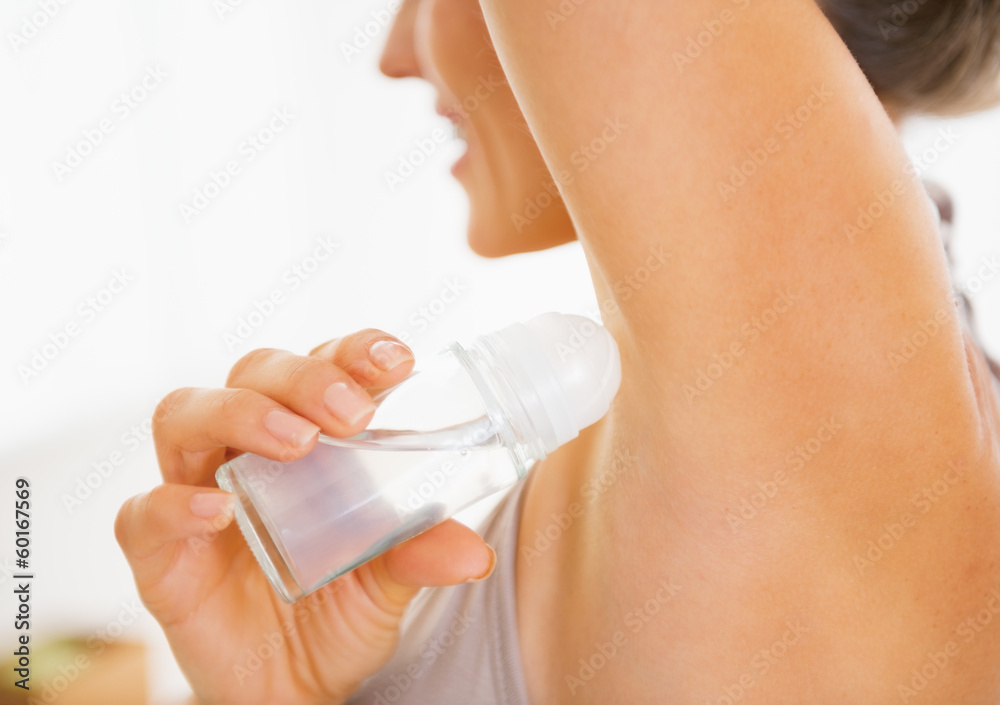 Closeup on young woman applying deodorant on underarm Closeup on young woman applying deodorant on underarm