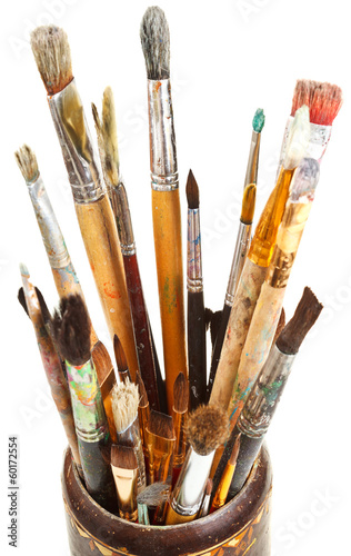 many used artistic paintbrushes in wooden cup