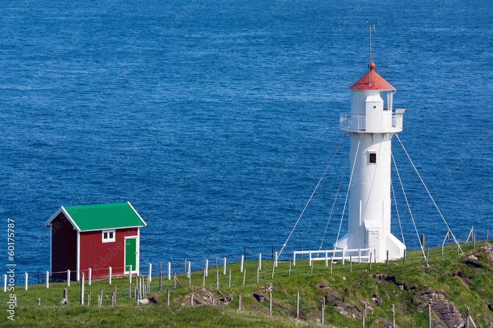 White lighthouse and red cabin on a sea cliff