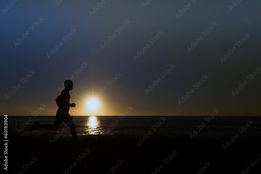 Silhouette of jogger along ocean horizon at sunset